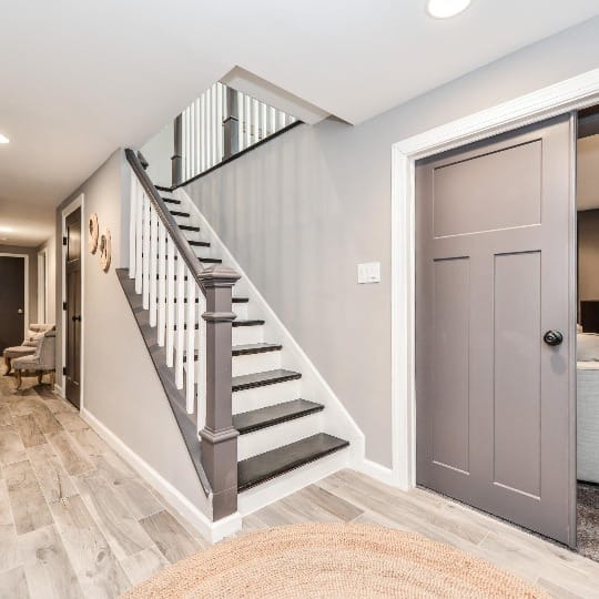 A white and grey remodeled basement with a staircase in a Northern Virginia home